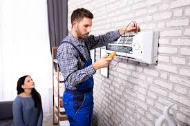 Teknik servis çalışanı klima montajı veya tamiri yaparken; iç ünite ve bağlantı ekipmanları görünmekte